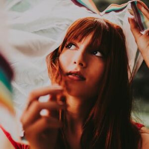 Beautiful portrait of a redheaded woman with a dreamy expression under a fabric outdoors.