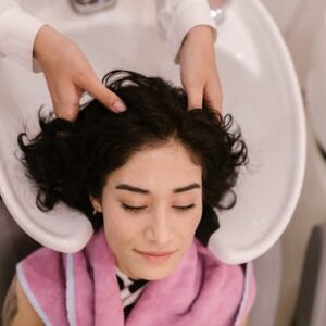 A serene woman enjoys a hair wash and massage at a contemporary hair salon.